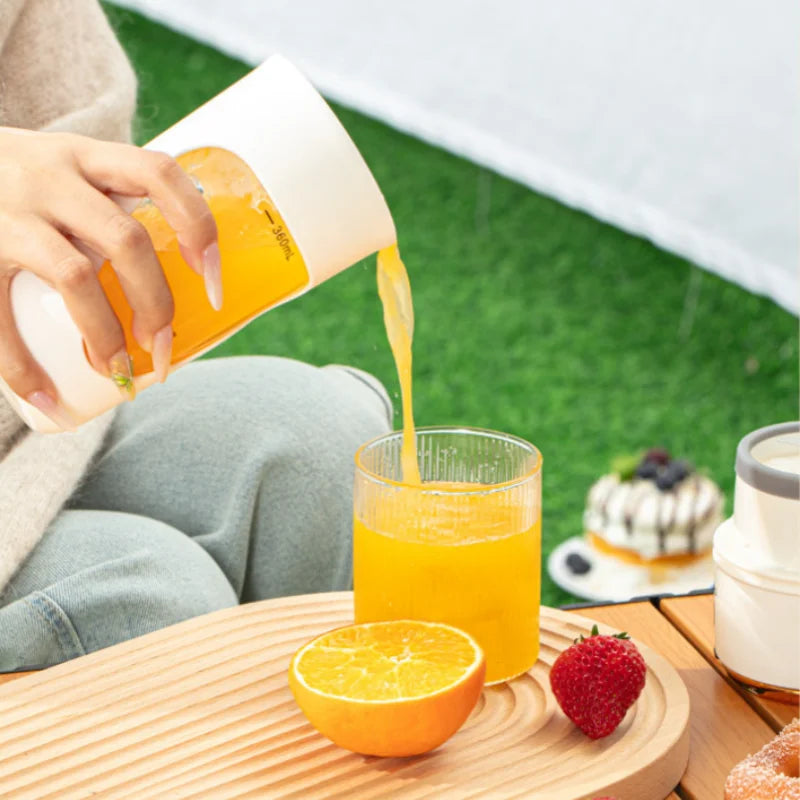 a person pouring orange juice into a glass from portable blender